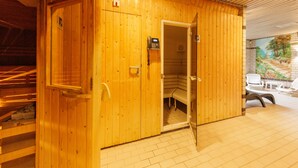 Una sauna de madera con puerta, un teléfono y un banco en su interior.