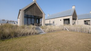 Un bâtiment moderne doté d’une grande entrée, d’un espace extérieur aménagé avec des sièges et d’un chemin menant à l’entrée.