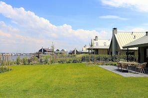 A well-maintained lawn, outdoor seating, and a view of a body of water. - Villa Oesterdam 2+2 Persons (Tholen)