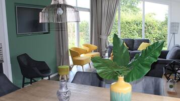 A dining area with a wooden table, a vase with a plant, and a hanging light fixture.