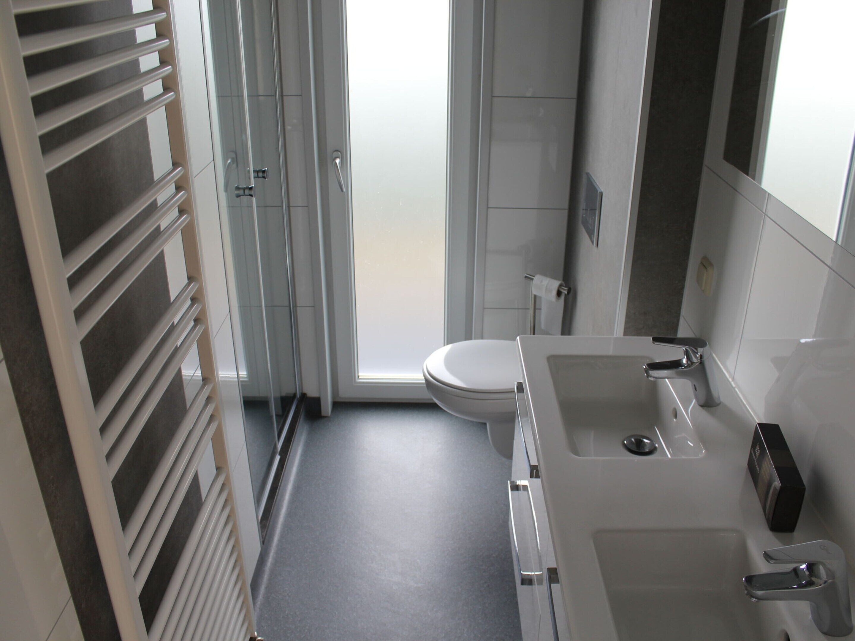 Ein Badezimmer mit Toilette, Waschbecken und Duschbereich.