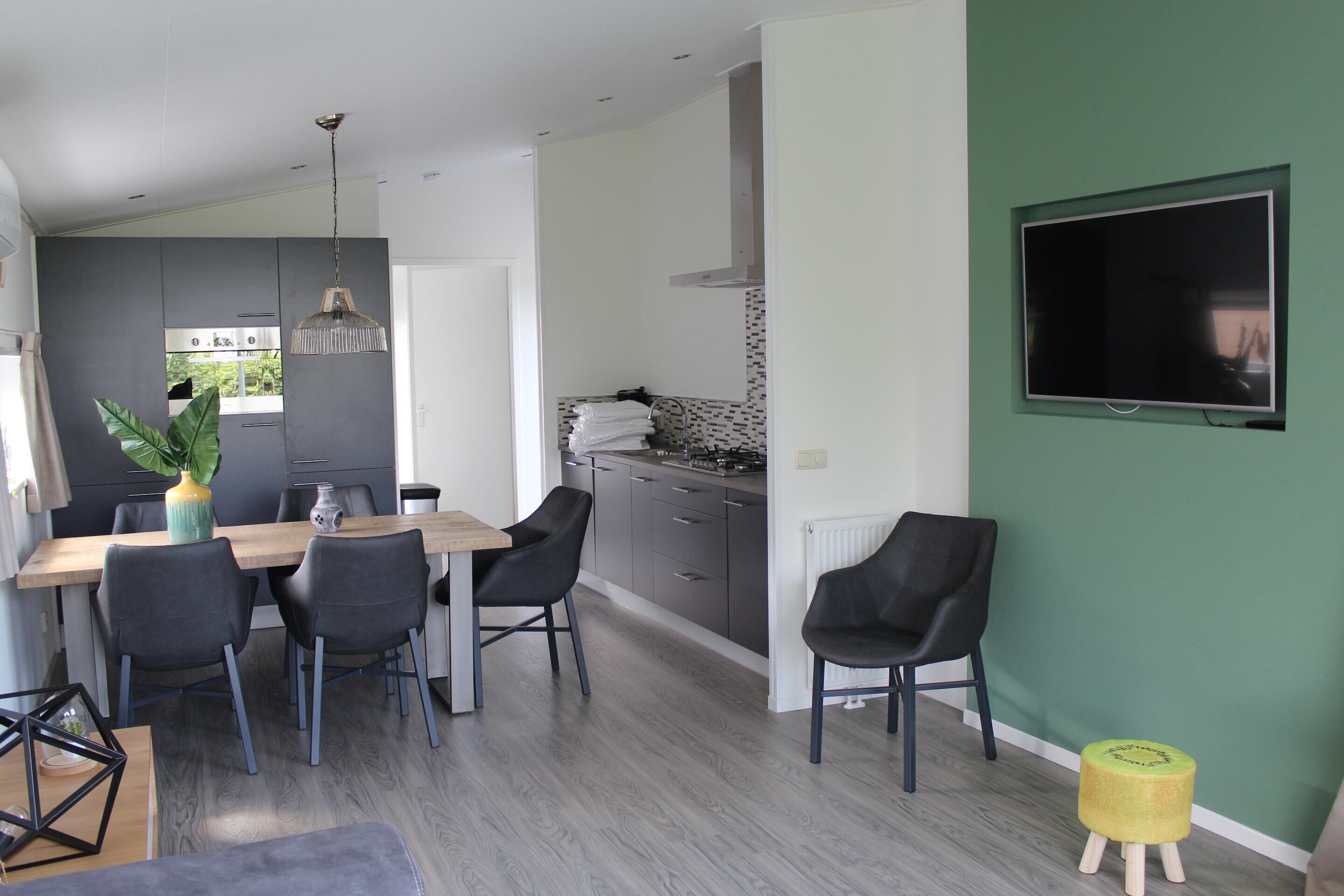 A modern kitchen with grey cabinets, a wooden dining table, and black chairs.