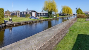 Una propiedad junto a un canal con varias casas, un barco atracado en el agua y un área verde bien cuidada.