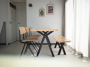 A dining area with a wooden table and chairs, a black metal frame, and a framed picture on the wall. - Modern Lodge With Dishwasher, Near the Beach (Zandvoort)