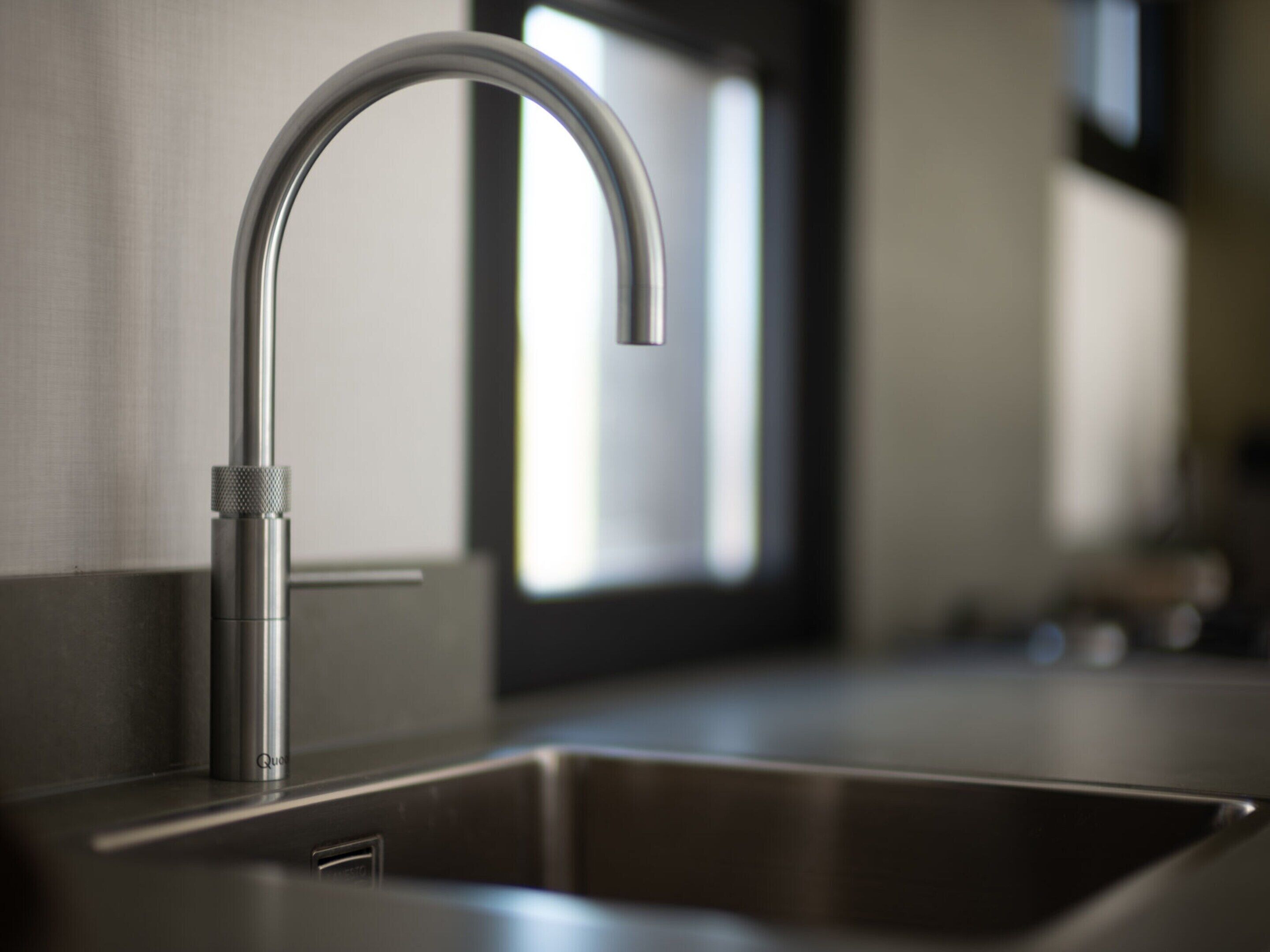 A modern kitchen with a stainless steel sink and faucet.