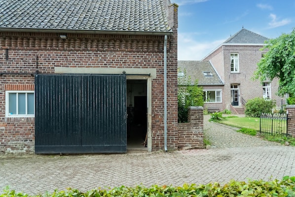 A brick building with a large black gate, a paved driveway, and a brick wall. - Limburg Mansion With Spa Near Forest (Swolgen)