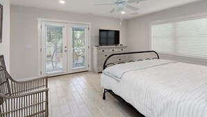 Un dormitorio con cama, ventilador de techo, televisión y cómoda.