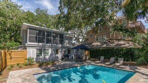 Una casa moderna con piscina, mobiliario de patio y valla de madera.