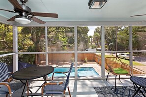 A sunroom with a ceiling fan, a pool, and outdoor seating. - Pet Friendly with private pool and fenced yard! (Saint Simons Island)