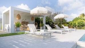 A modern outdoor pool area with white lounge chairs and umbrellas, surrounded by greenery and a clear sky. - 🌴 5 Bed Villa, Ocean View , Pool with Jacuzzi, Near Crane beach🌴 (Saint Philip)
