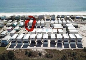 A beachfront property with multiple white buildings arranged in rows, each with a flat roof and a small front porch.