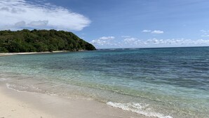 A beach with clear turquoise water, a sandy shore, and a forested hill in the background. - NEW! Luxury villa with private pool (sainte anne)