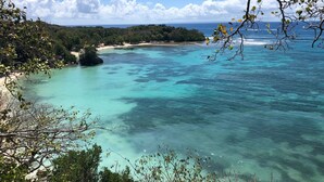 A coastal landscape with clear turquoise waters, a sandy beach, and dense greenery. - NEW! Luxury villa with private pool (sainte anne)