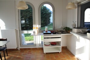 A kitchen with white cabinetry, a dining table with chairs, and a view of greenery outside.