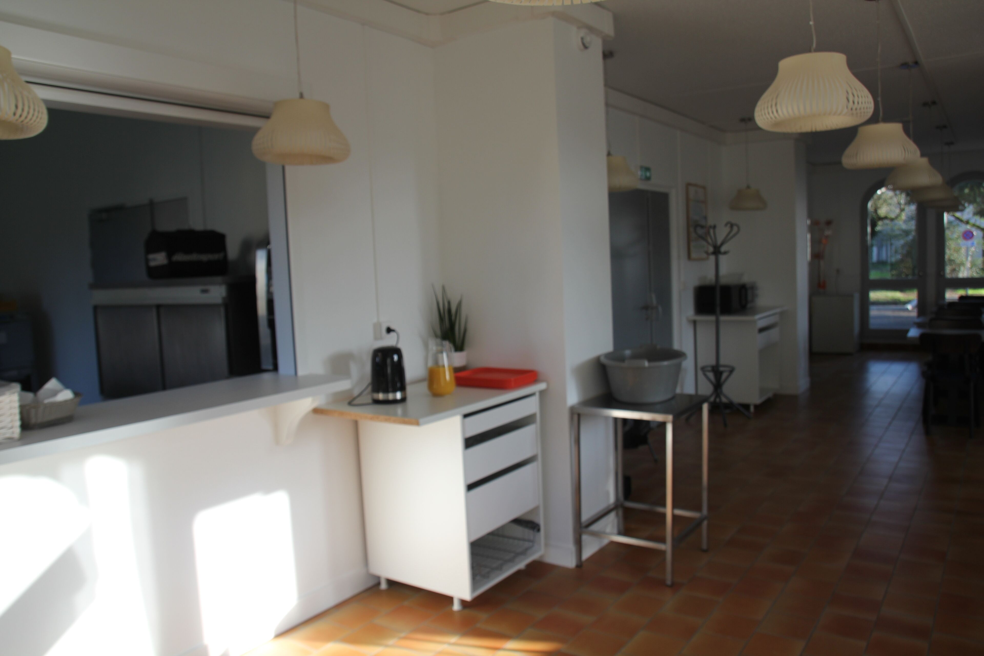 Une cuisine moderne avec des meubles blancs, un plan de travail et des luminaires suspendus.