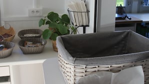 A kitchen with wicker baskets, a potted plant, and a window with a view of the outdoors. - Auberge de Jeunesse Orléans Centre Ville - Hostel (Orléans)