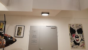 A multi-level interior with a staircase, a door with opening hours, and artwork on the walls. - Auberge de Jeunesse Orléans Centre Ville - Hostel (Orléans)