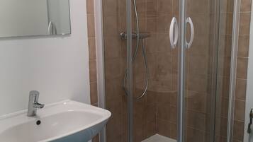 A bathroom with a glass-enclosed shower, a white sink, and a toilet.