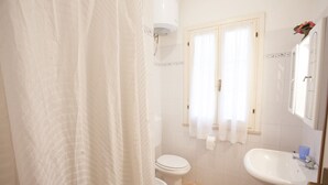 A bathroom with a toilet, sink, and shower curtain. - APP.TI VILLA ANNA - VILLA ANNA - TRILO PRIMO PIANO (Capoliveri)