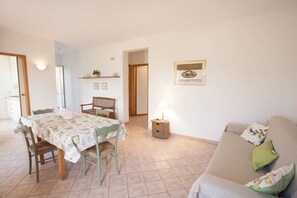 Una sala de estar con una mesa de comedor, sillas, un sofá y una lámpara.