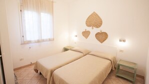 A room with two beds, a window with sheer curtains, and wall-mounted light fixtures. - APP.TI VILLA ANNA - VILLA ANNA - TRILO PRIMO PIANO (Capoliveri)