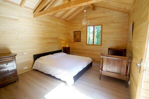 Un dormitorio de cabaña de madera con cama, cómoda y una mesita.