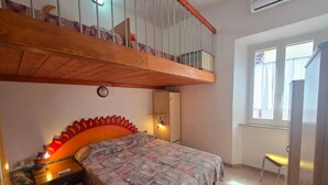 A bedroom with a bed, a nightstand, a desk, a chair, and a window. - SOLILUNA on the seafront of Cavo (Rio Marina)