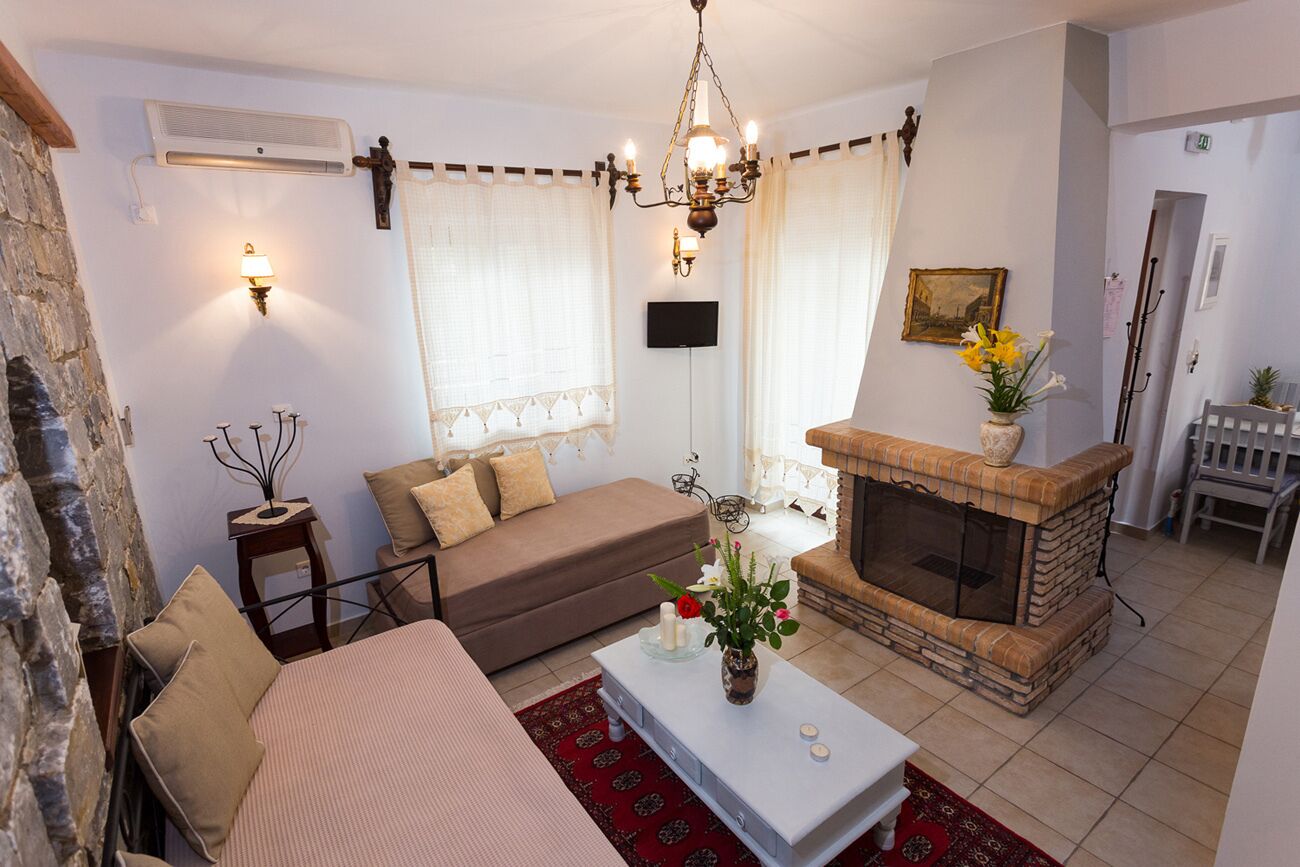 A cozy living room with a sofa, a coffee table with candles, a fireplace, and a stone wall.