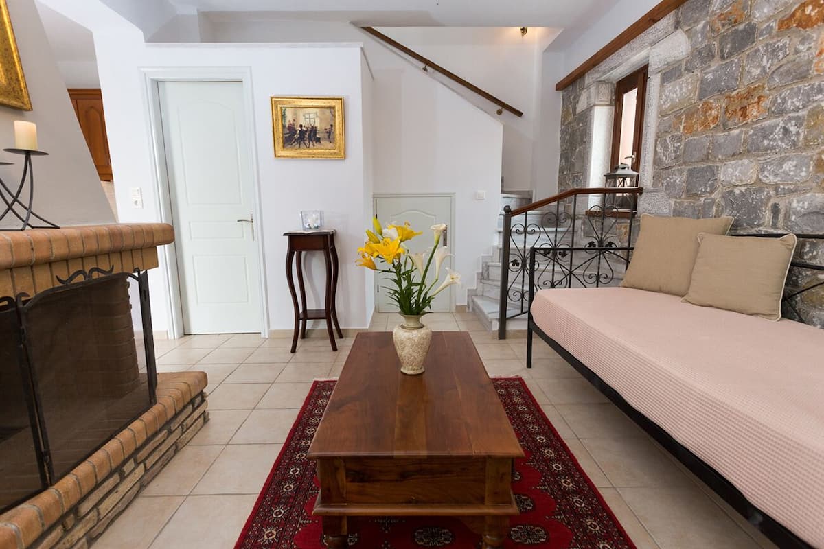 A living room with a fireplace, a sofa, a coffee table, and a staircase leading to an upper floor.