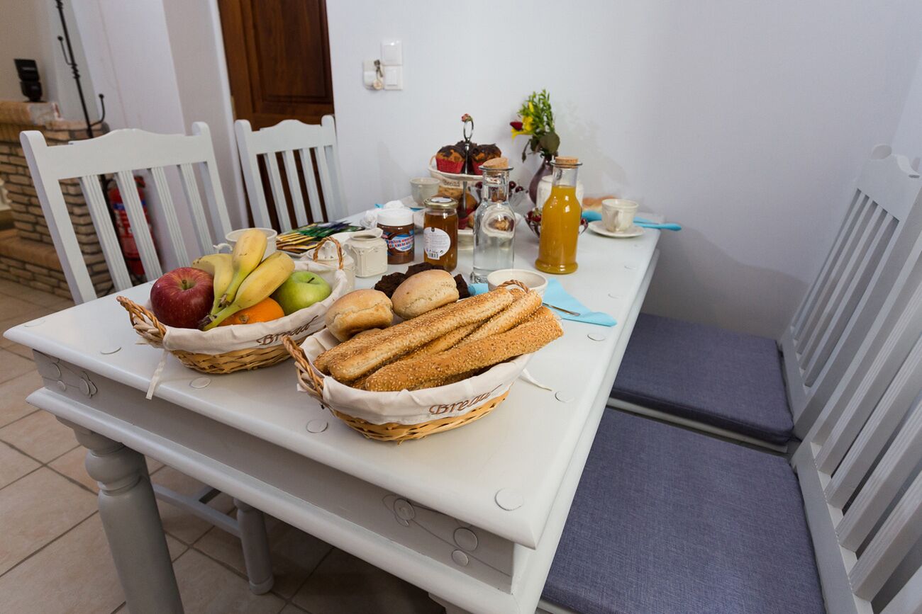 A dining table with baskets of bread, fruits, and condiments.