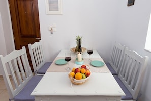 Una mesa de comedor servida con una cesta de frutas, copas de vino y una vela.