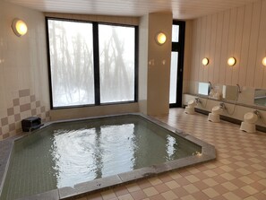 A spa room with a large window, a hot tub, and a shower area. - Wadano Forest Apartments (Hakuba)