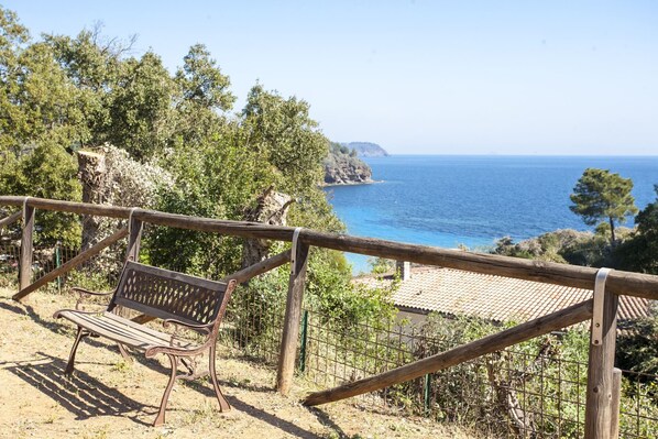 A wooden bench overlooking a coastal view with a clear sky.