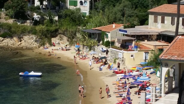 A beach with clear water, people sunbathing, and a boat. - APP.TI BAIA BLU - BAIA BLU 3 (Portoferraio)