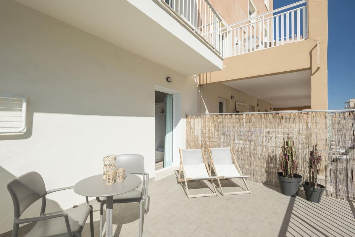 Ein Balkon mit Tisch, Stühlen, Topfpflanzen und Blick ins Innere des Gebäudes.