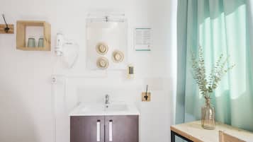 Un baño con lavamanos, espejo y secador de pelo en la pared.