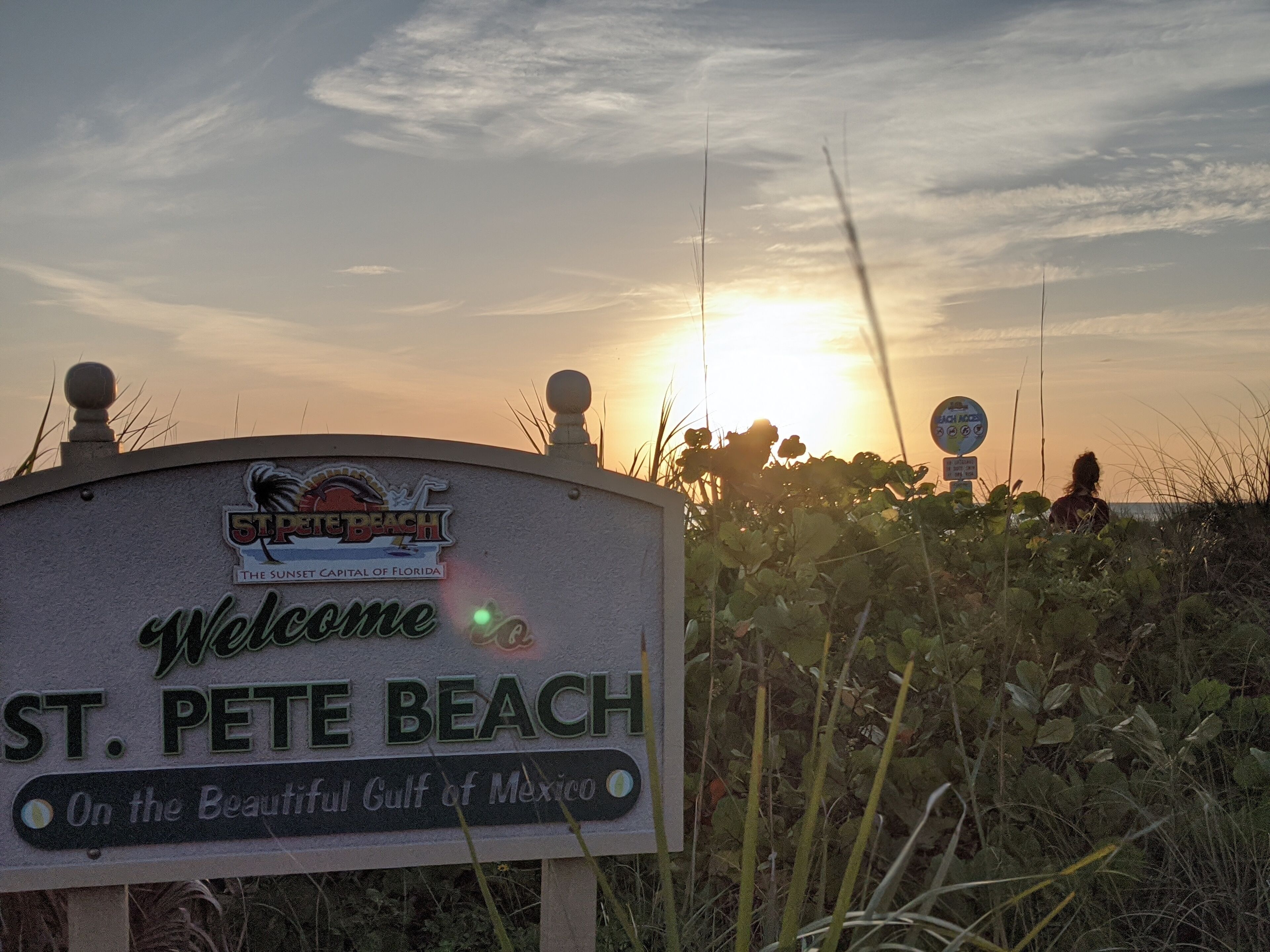 Un panneau d’accueil pour St. Pete Beach, avec un coucher de soleil en arrière-plan.