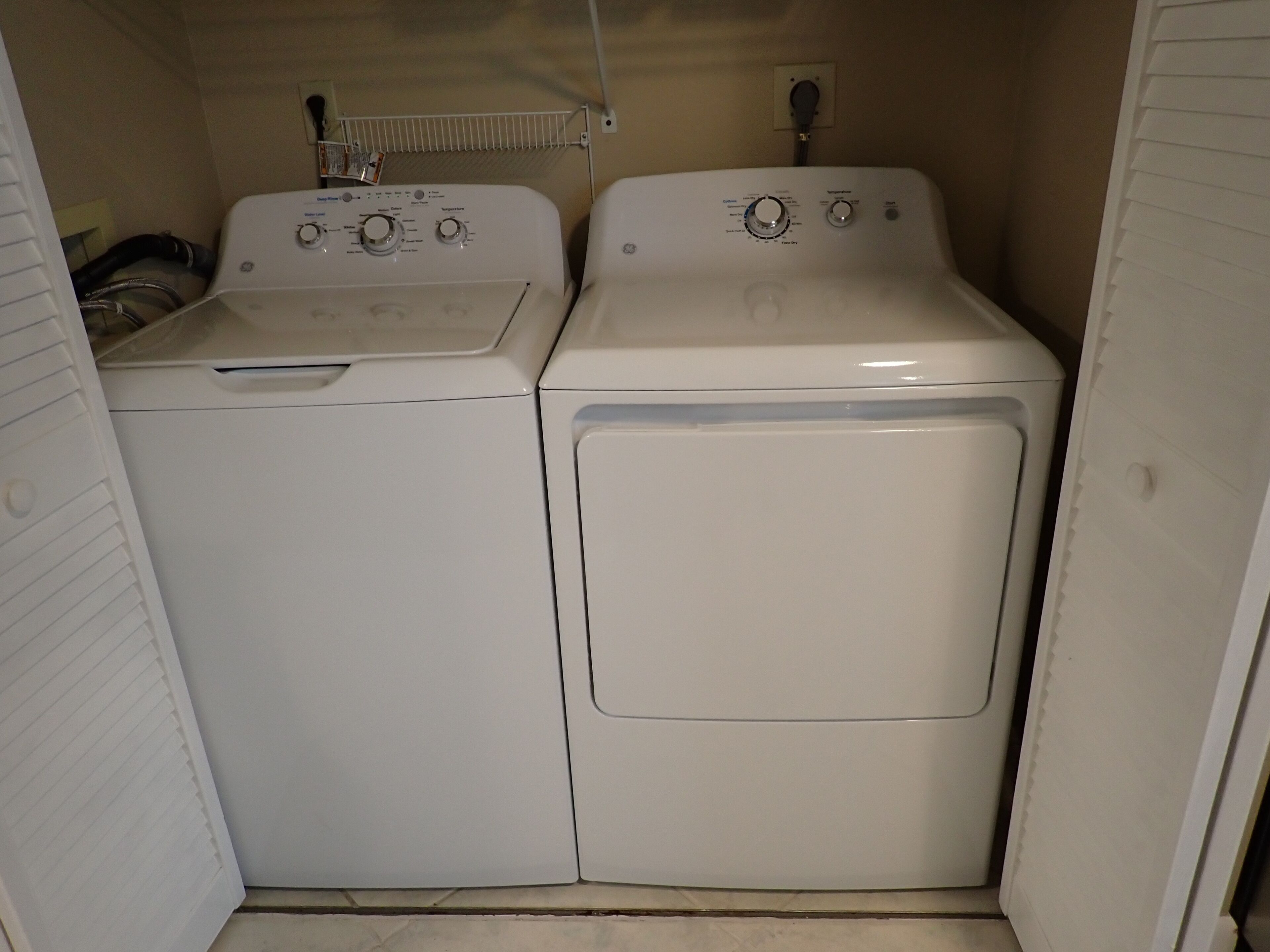 A compact laundry room with two stacked washing machines and a drying rack.
