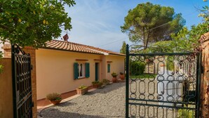 A house with a gravel driveway, a metal gate, and potted plants. - APP.TI BAIA BLU - BAIA BLU 5 (Portoferraio)