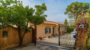 A rustic house with a tiled roof, a gravel driveway, and a metal gate. - APP.TI BAIA BLU - BAIA BLU 5 (Portoferraio)