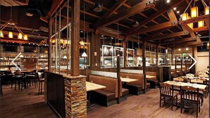 Un restaurante con vigas de madera, pilares de piedra y varias zonas de estar, incluyendo cabinas y mesas.