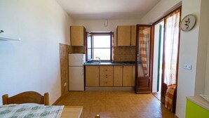 Una cucina compatta con mobili in legno, un frigorifero integrato e una finestra con tende.
