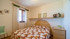 Una camera da letto con un letto, una sedia, una cassettiera e una finestra con tende.
