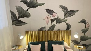 A bedroom with a bed, two bedside tables with lamps, a wooden headboard, and a floral wall mural. - APPARTAMENTI SERENA - MONO/TRILO - APPARTAMENTO TRILO SERENA (Capoliveri)