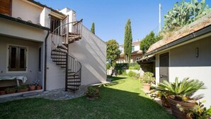 A residential property with a spiral staircase leading to a second floor, a well-maintained lawn, and various potted plants. - APPARTAMENTI SERENA - MONO/TRILO - APPARTAMENTO TRILO SERENA (Capoliveri)