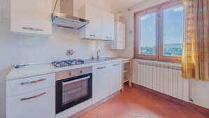 Une cuisine avec des meubles blancs, une cuisinière à gaz, un four et une fenêtre donnant sur un beau paysage.