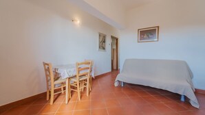Une petite pièce comprenant une table et des chaises, un lit et une porte donnant sur une autre pièce.