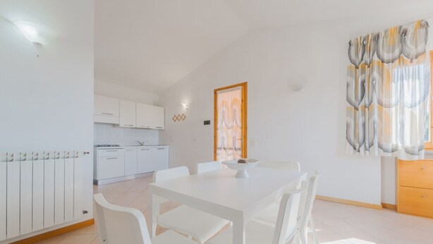 A modern kitchen with white cabinets and a dining area with a white table and chairs.