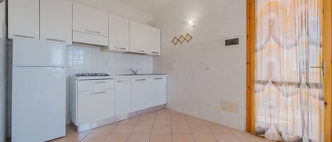 A kitchen with white cabinets, a stove, and a refrigerator.