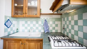 A kitchen with wooden cabinets, a gas stove, a sink, and checkered backsplash tiles. - APP.TI MORCONE - MORCONE BILO 1 (Capoliveri)